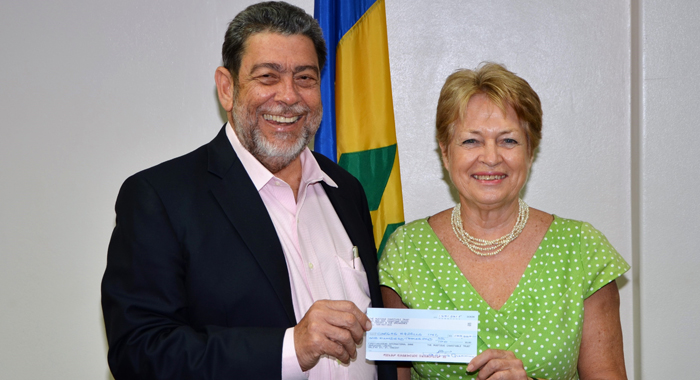 Lavinia Gunn, administrator of the Mustique Charitable Trust hands over a cheque for EC$100,000 towards the purchase of a school bus to Prime Minister Ralph Gonsalves.