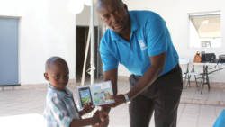 President of the PCCU, Junior Simmons, presenting a tablet to a Junior Saver.