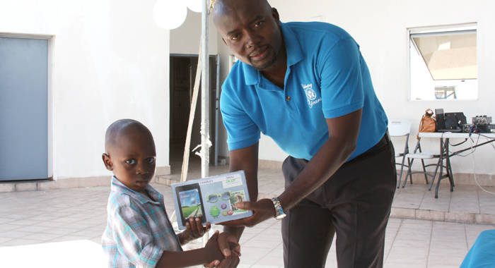 President of the PCCU, Junior Simmons, presenting a tablet to a Junior Saver.