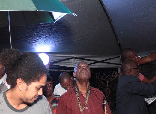 Persons shelter rain under a leaky tent at the Human Rights Association'r prayer and peace rally last weekend. (IWN photo)