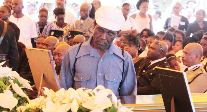 A man stares at one of the caskets at the funeral on Sunday. (IWN photo)