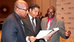 From left: Ellsworth Dacon, Sen. Camillo Gonsalves, and Hon. Clayton Burgin peruse a document after the announcement in Abu Dhabi on Sunday. (Photo: CMC/IWN)