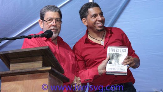 Prime Minister Dr. Ralph Gonsalves presents a book to his son, Sen. Camillo Gonsalves at the ULP's rally on Saturday. (IWN photo)