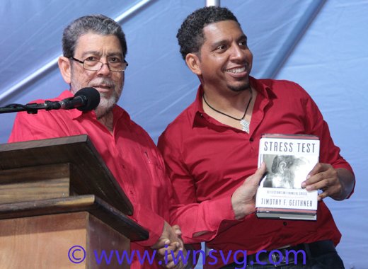 Prime Minister Dr. Ralph Gonsalves presents a book to his son, Sen. Camillo Gonsalves at the ULP's rally on Saturday. (IWN photo)