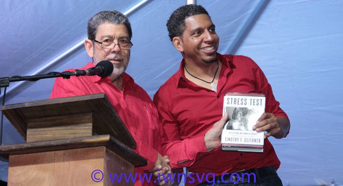 Prime Minister Dr. Ralph Gonsalves presents a book to his son, Sen. Camillo Gonsalves at the ULP's rally on Saturday. (IWN photo)