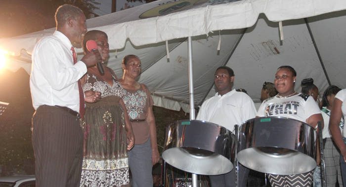 Former MP for North Leeward, Jerrol Thompson comments, as Nichola Evans of the NCCP prepares to present the pans. (IWN photo)