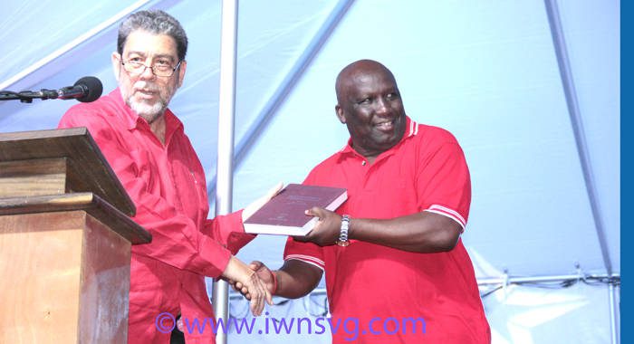 PM Dr. Ralph Gonsalves presents a book to Jimmy Prince, who is tipped to be the ULP's candidate in Marriaqua. (IWN photo)