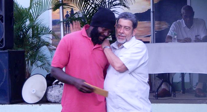 Prime Minister Dr. Ralph Gonsalves makes the presentation to a recipient in Colonairie on Friday. (Photo: NBC Radio/Facebook)