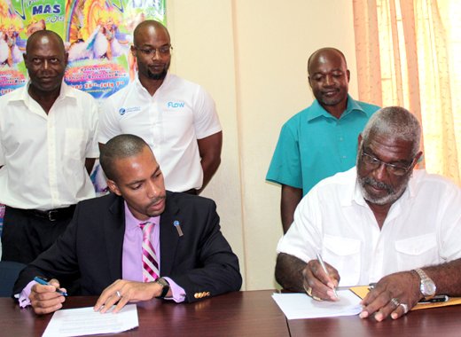 Christopher Gordon of FLOW, left, and Dennis Bowman of CDC, sign the contract while staff of both entities look on. (IWN photo)