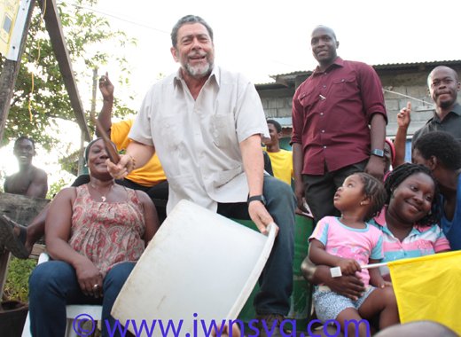 PM Dr. Ralph Gonsalves beats a "drum" and shouts "Labour" in Fitz Hughes on Friday as protestors and his bodyguards look on. (Photo: Zavique Morris-Chance/IWN)