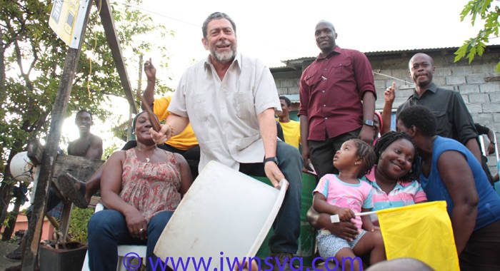 PM Dr. Ralph Gonsalves beats a "drum" and shouts "Labour" in Fitz Hughes on Friday as protestors and his bodyguards look on. (Photo: Zavique Morris-Chance/IWN)