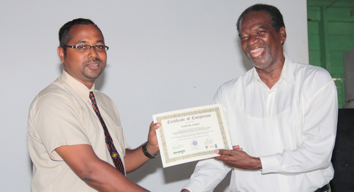 Stanton Gomes, one of the founders of Radio Grenadines receives his certificate from Bernard Joseph. (IWN photo)