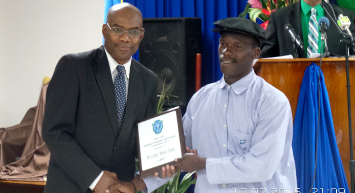 Featured speaker Dr. Lennox Adams presents an award to top coach Carlton "Morna" Dennie. (Photo: E. Glenford Prescott)