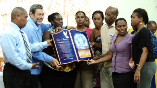 Relatives of the students involved in the Rock Gutter bus crash on Thursday present a plaque of appreciation to Prime Minister Ralph Gonsalves.