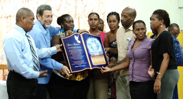 Relatives of the students involved in the Rock Gutter bus crash on Thursday present a plaque of appreciation to Prime Minister Ralph Gonsalves.