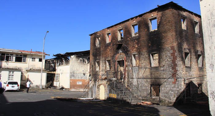 The government will demolish the buildings gutted by fire, including this brick building, left, from the nation's colonial past. (IWN photo)