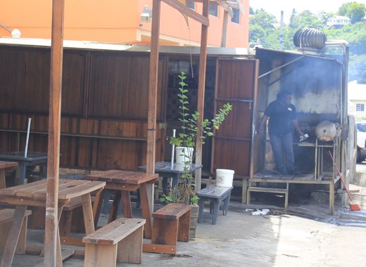 A man fires up barbeque pits in Arnos Vale on Wednesday. Residents have complained about noise and smoke in the area. (IWN photo) 