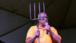 NDP candidate for West St. George, Dr. Julian "Jules" Ferdinand holds up a garden fork at his party's rally in Campden Park Saturday night. (IWN photo)