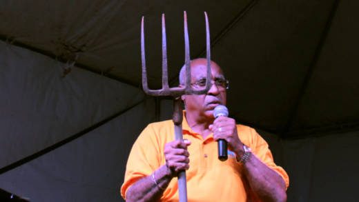 NDP candidate for West St. George, Dr. Julian "Jules" Ferdinand holds up a garden fork at his party's rally in Campden Park Saturday night. (IWN photo)