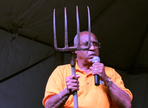 NDP candidate for West St. George, Dr. Julian "Jules" Ferdinand holds up a garden fork at his party's rally in Campden Park Saturday night. (IWN photo)