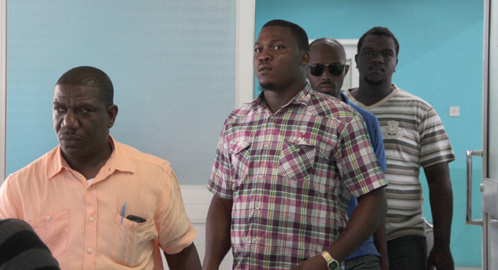 Lawyer Israel Bruce, left, burglary suspect, Kamorni Antoine, and police officer exiting the arrivals hall at the E.T. Joshua Airport on Sunday. (IWN photo)