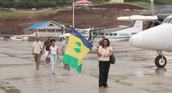 Director of Airports, Corsel Robertson waves an SVG flag after disembarking one of the four aircraft at Argyle. (IWN photo)