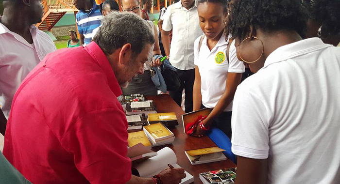 Prime Minister Ralph Gonsalves gives Community College students copies of his books after a question and answer session organised by the college last week. (Photo: Lance Neverson/Facebook)