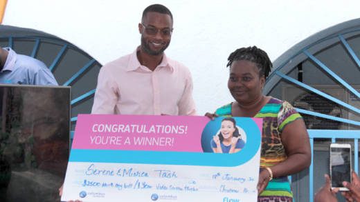 Serene Tash, right, collects here prize in FLOW Christmas promotion from the company's Corey Garrett. (IWN photo)