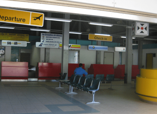 The only occupant (a security guard) in the tiny terminal at Sir James F. Mitchell Airport in front of an out-of-date LIAT sign.