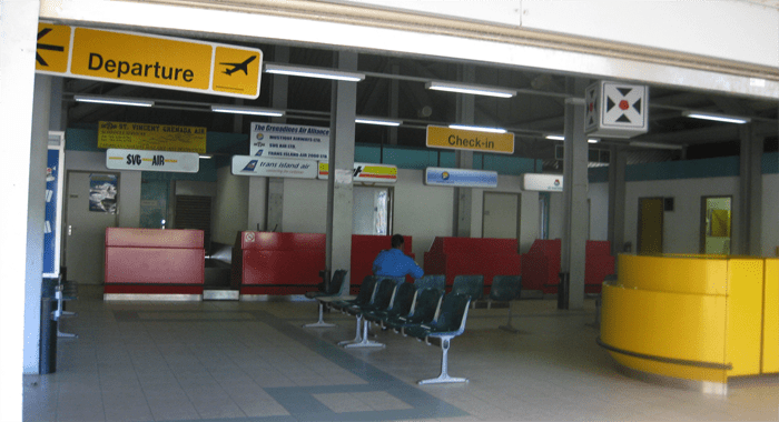 The only occupant (a security guard) in the tiny terminal at Sir James F. Mitchell Airport in front of an out-of-date LIAT sign.