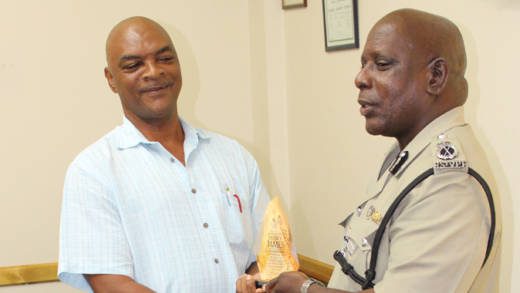 ASP Sydney James, left, receives a token from Commissioner of Police Michael Charles.