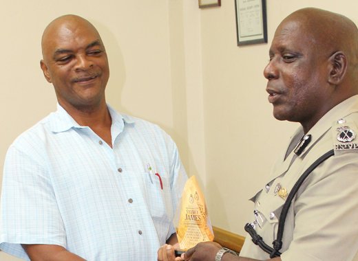 ASP Sydney James, left, receives a token from Commissioner of Police Michael Charles.