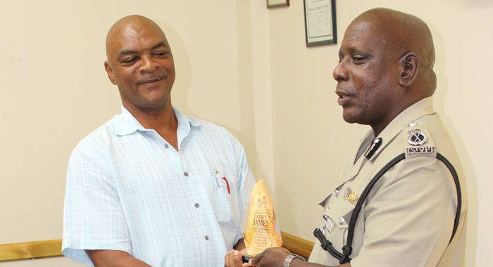 ASP Sydney James, left, receives a token from Commissioner of Police Michael Charles.