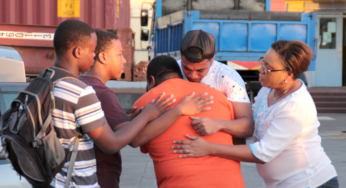 Grammar School teacher, Randy Boucher, is consoled at the Grenadines Wharf on Saturday. (IWN photo)