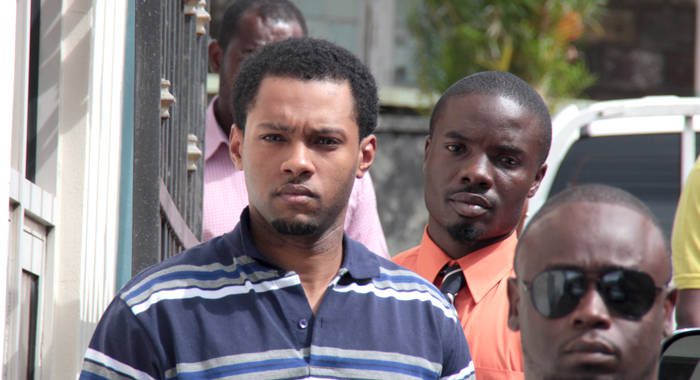 In this April 22, 2016 photos, murder accused Veron Primus, left, appears in court, charged with Greaves' murder. He is escorted by detective Constable Edmond Ollivierre, the lead investigator, who testified on Tuesday.  (iWN photo)