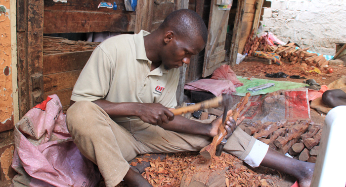 A man carves wooden art outside a craftshop in a slum area of Dakar. (IWN photo)