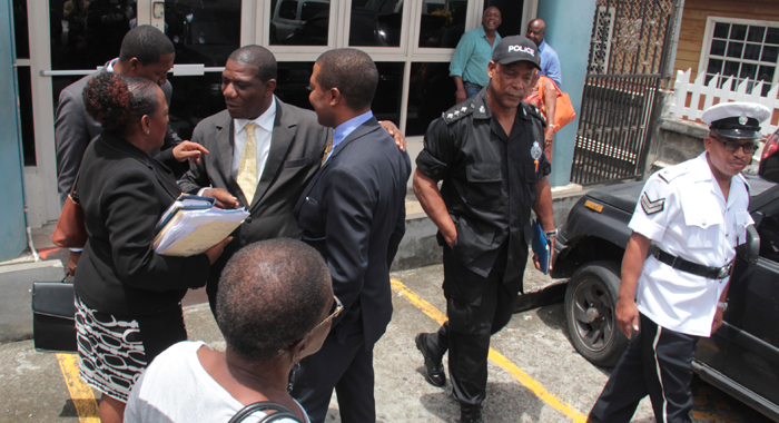 Monday's hearing was initially expected to see the defence cross-examining Assistant Superintendent of Police Timothy Hazelwood, who is seen here (in black uniform) leaving the court as Exeter and his lawyers speak outside the courthouse on Monday. (IWN photo)