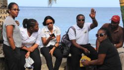 Workers at the spa at Buccament Bay Resort sit on the beachfront on Wednesday. They went on strike over non-payment of wages. (IWN photo)