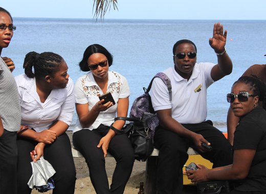 Workers at the spa at Buccament Bay Resort sit on the beachfront on Wednesday. They went on strike over non-payment of wages. (IWN photo)