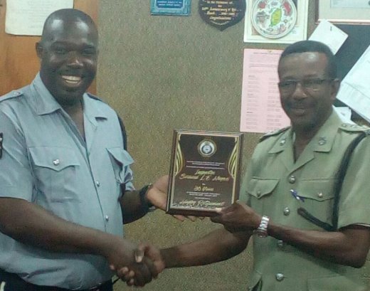 Sergeant Vaughn Miller of the Police Band, left, presents Inspector Bernard Haynes with a plaque.
