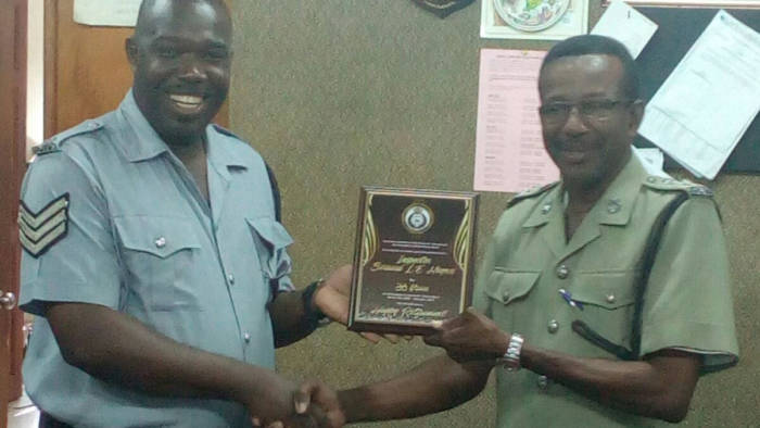 Sergeant Vaughn Miller of the Police Band, left, presents Inspector Bernard Haynes with a plaque.