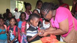 Jennifer Joseph-Butler hands out stationery items to children at a party in Rillan Hill on July 16. (IWN photo)
