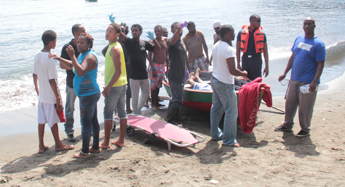 Physician Francis Murray (in white t-shirt) prepares to examine the body of Giovanni Sutherland-Sam. (IWN photo)