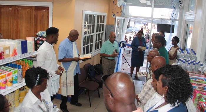 Deacon Victor Peters blesses the pharmacy on Bay Street, Kingstown on Saturday. (IWN photo)