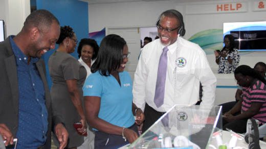 FLOW employee Maria DeGrads, centre, treats Director of Public Prosecution, Colin Williams, right, to an experience at the new FLOW store on Monday. (IWN photo)