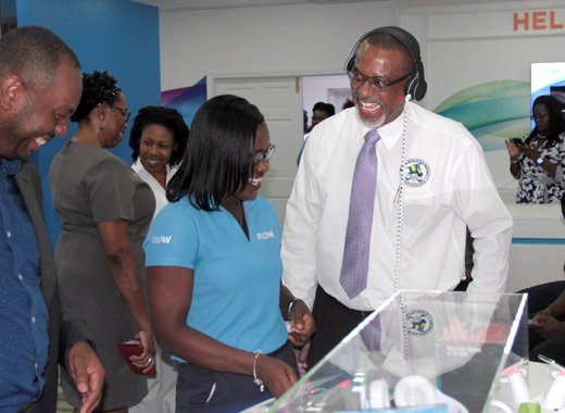 FLOW employee Maria DeGrads, centre, treats Director of Public Prosecution, Colin Williams, right, to an experience at the new FLOW store on Monday. (IWN photo)