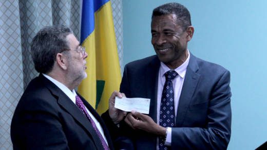 Prime Minister Dr. Ralph Gonsalves, left, receives the cheque from diplomat Fitz Huggins. (IWN photo)