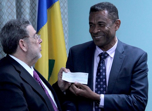 Prime Minister Dr. Ralph Gonsalves, left, receives the cheque from diplomat Fitz Huggins. (IWN photo)