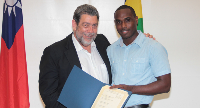 Clint Lewis, the first Vincentian to be awarded a scholarship to read for a PhD in Taiwan, receives his certificate from Prime Minister Gonsalves. (IWN photo)