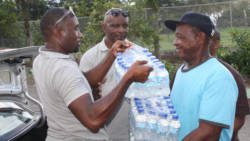 Chance, left, and Prescott, get some assistance in transporting the cases of water into the emergency shelter. (IWN photo)